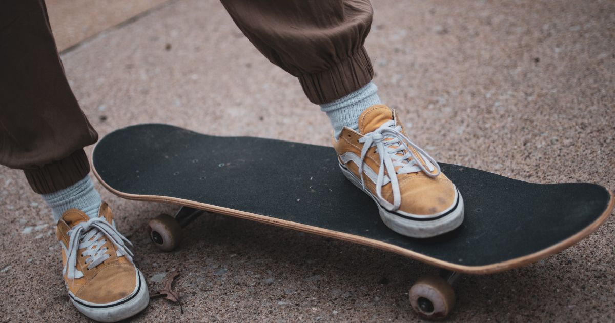 A Person in Yellow Sneakers Stepping on the Skateboard
